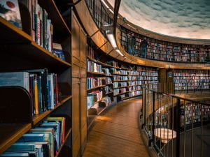 Image of dark wood library shelves filled with books that curve around the second-floor of a rotunda